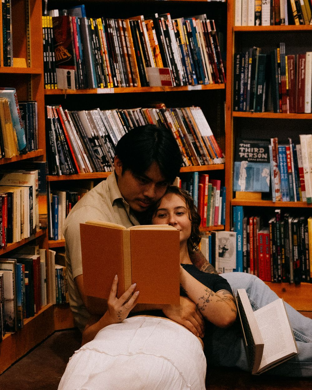 A closeup shot of a couple reading together on the floor.