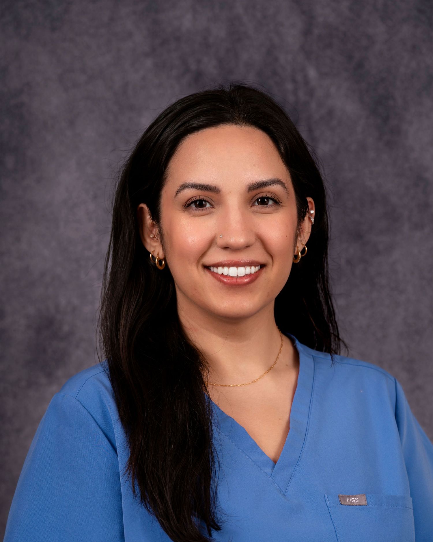 Professional headshot series in blue medical scrubs showing various poses against a grey backdrop.