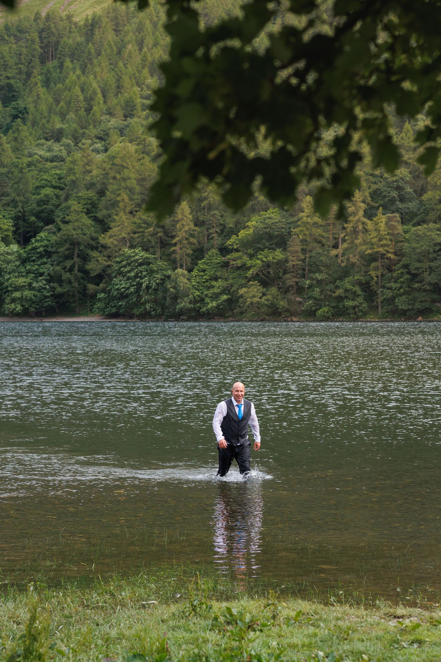A sequence of photos showing someone gracefully diving backwards into a serene mountain lake surrounded by evergreen forest.