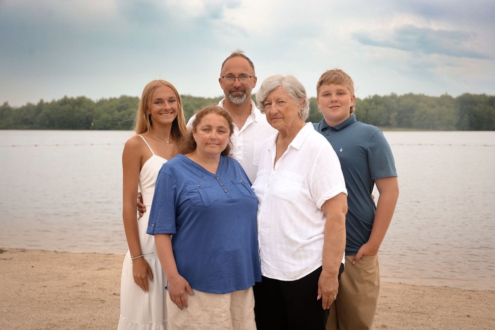 A small group gathers for a casual outdoor photo by the lake on a summer evening.