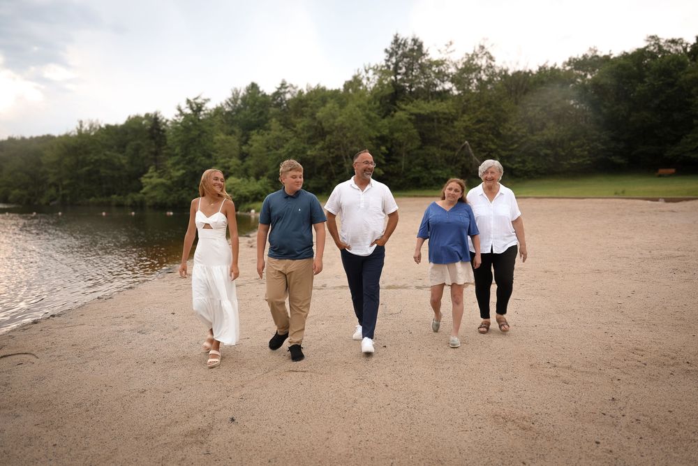 Family members walk together along a sandy beach path during a sunset photo session at golden hour.