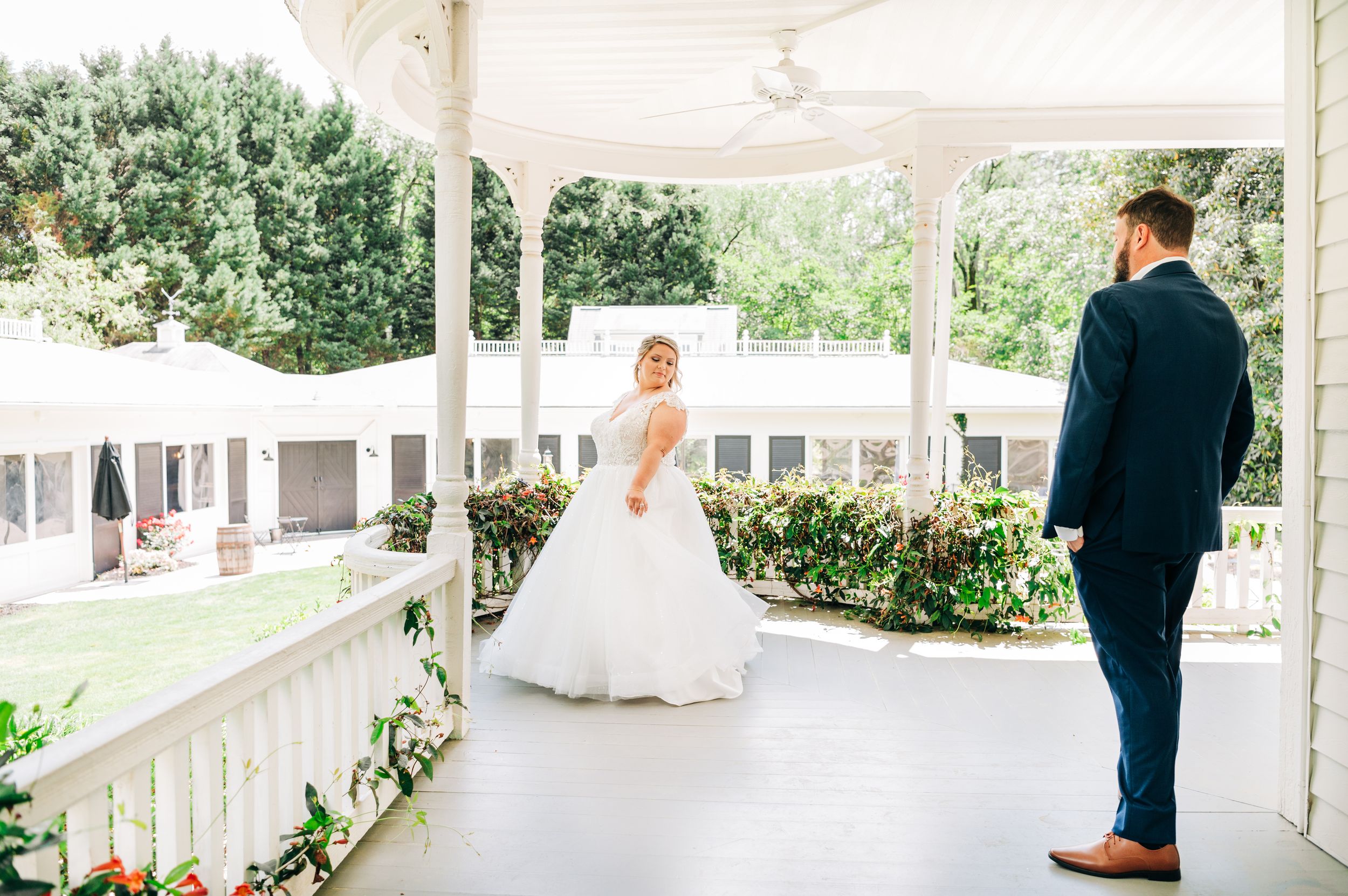 A wedding couple shares intimate moments on a white gazebo surrounded by lush greenery and natural light.