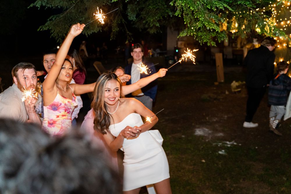 Wedding celebration at night with guests holding sparklers and dancing.