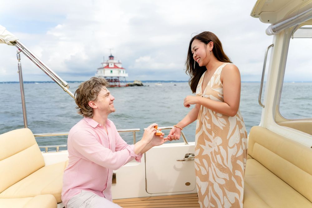 A romantic marriage proposal takes place on a boat deck with a lighthouse visible in the background.