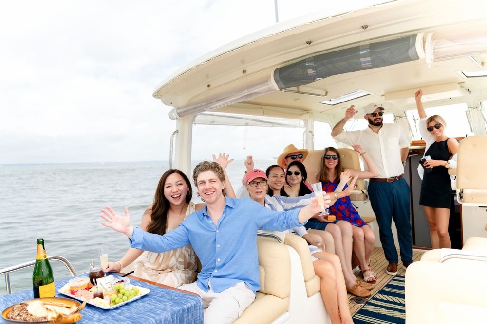 Group enjoying a festive boat party with drinks and snacks while sailing on a luxury yacht at sea.