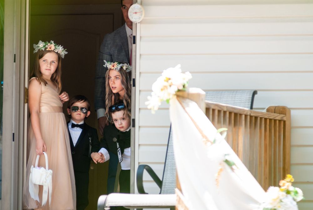 Wedding party peeking out from doorway in playful pose.