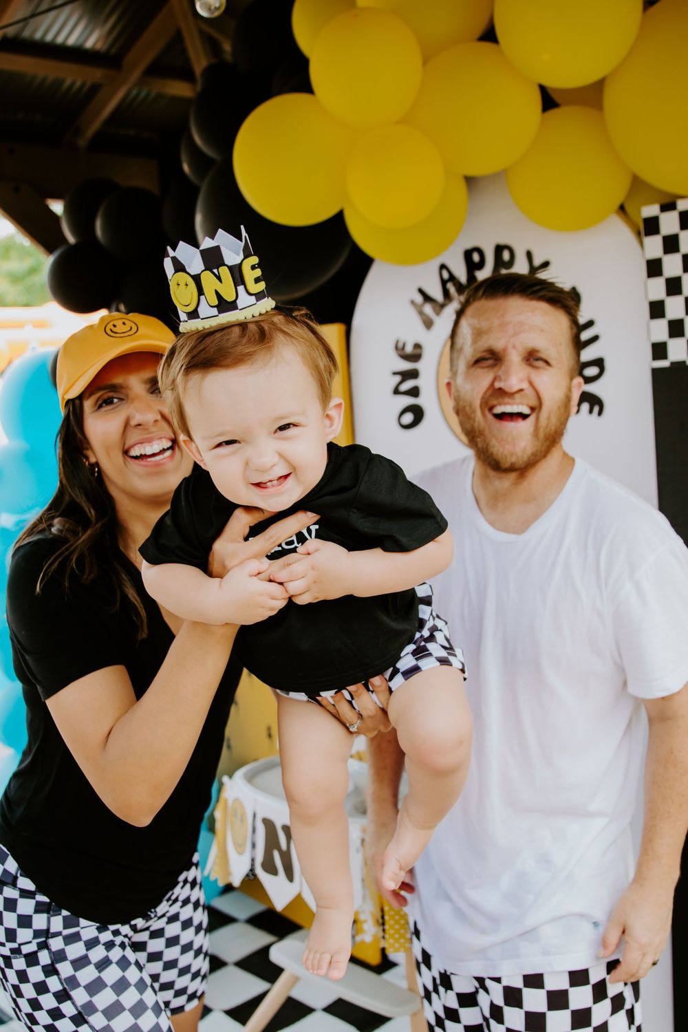 Racing themed first birthday party with yellow and black balloon arch decor.