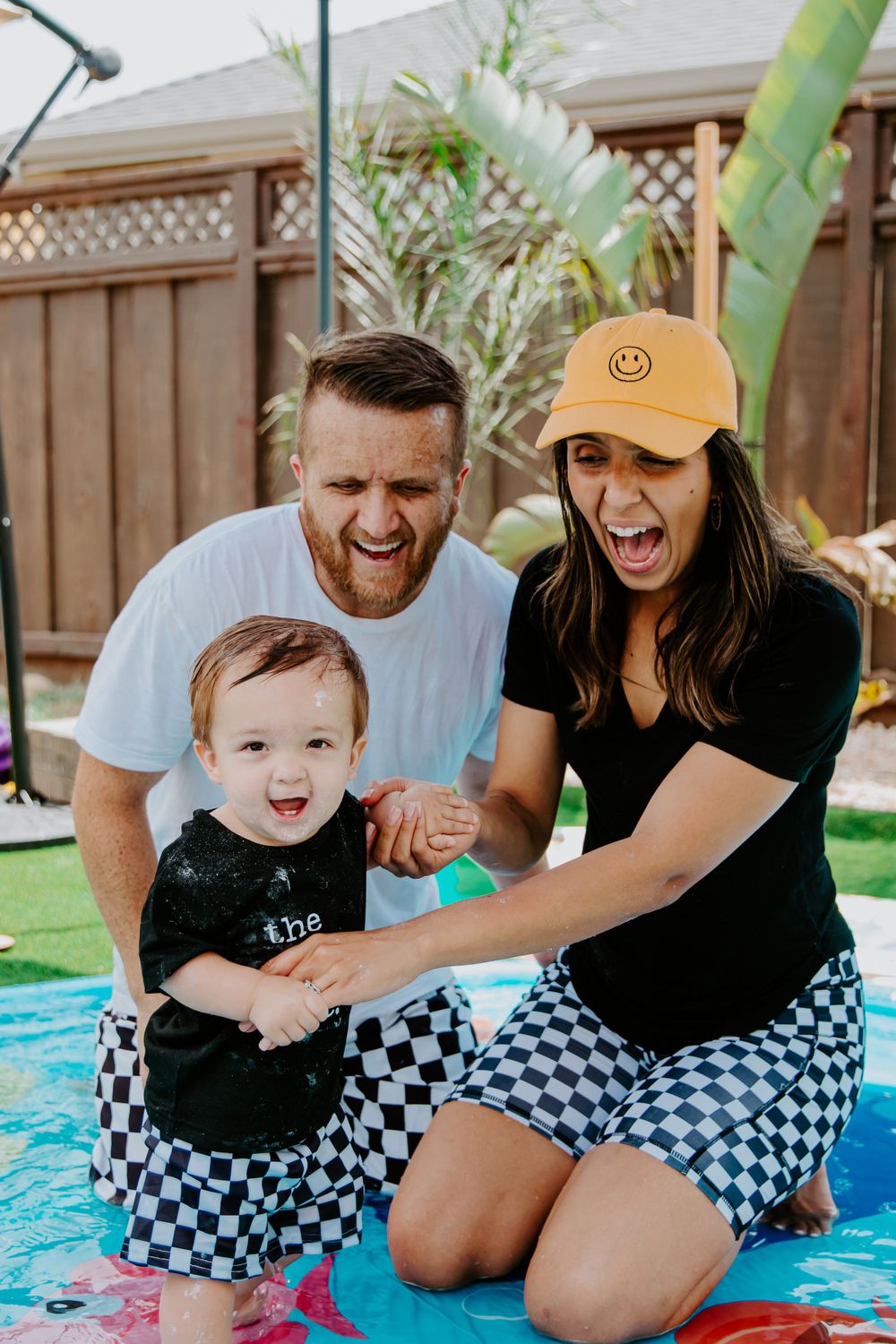 Happy family moment outdoors by the pool with matching checkered outfits.