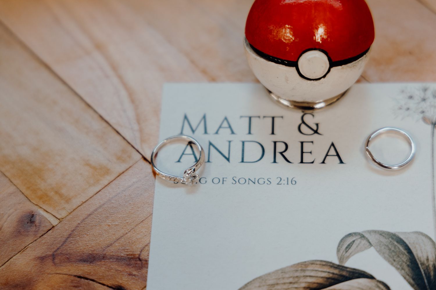 Pokeball prop and wedding rings displayed on wedding invitation.