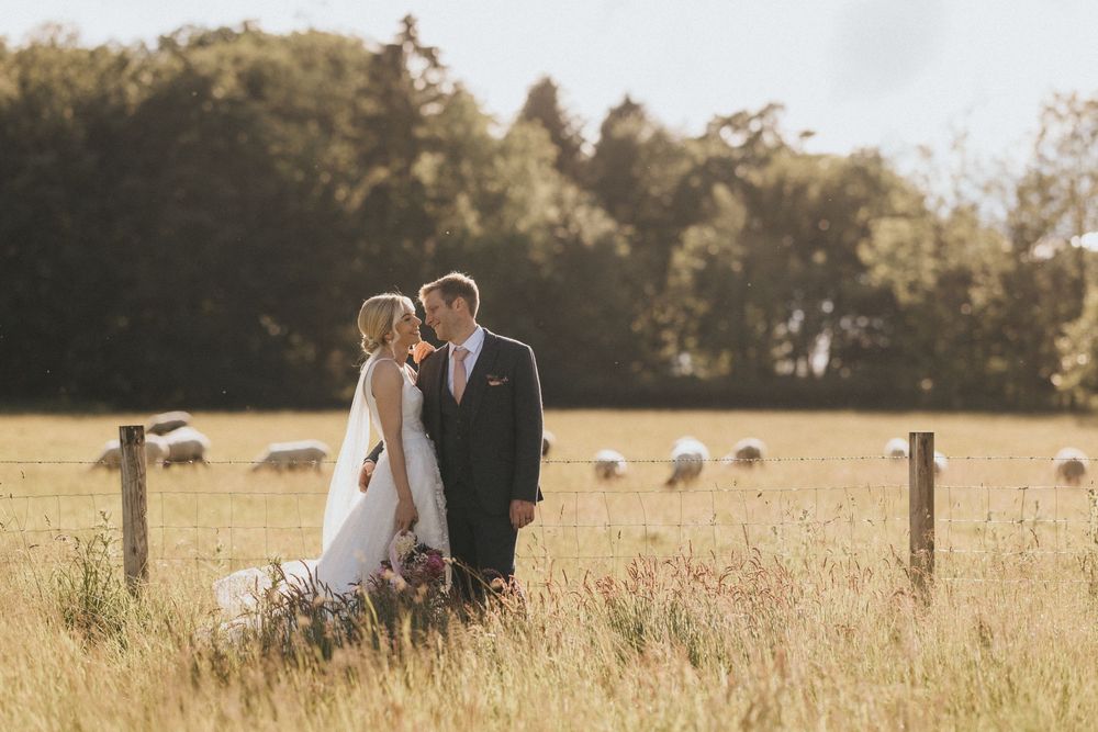 A couple in wedding attire stands together in a golden wheat field during at Scrivelsby Walled Garden.