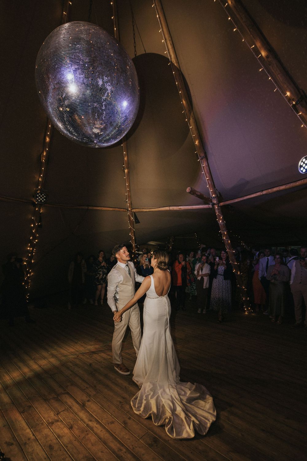 A weddingcouple shares their first dance under a glittering disco ball in a rustic venue at Scrivelsby Walled Garden.