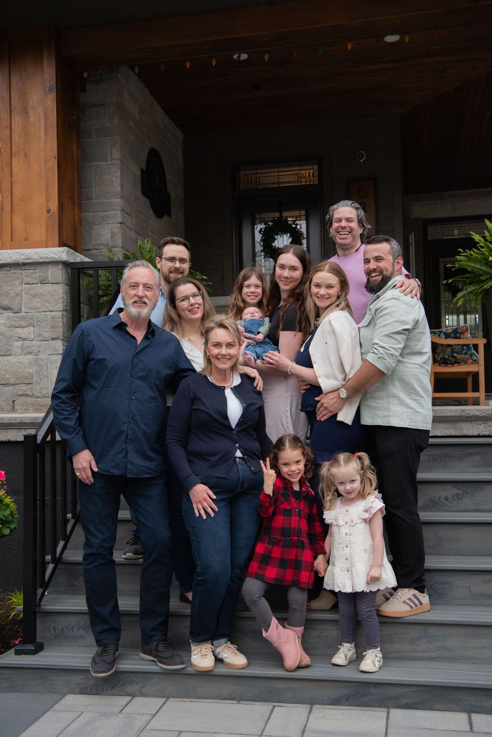 Family group portrait sitting together on outdoor stone porch steps.