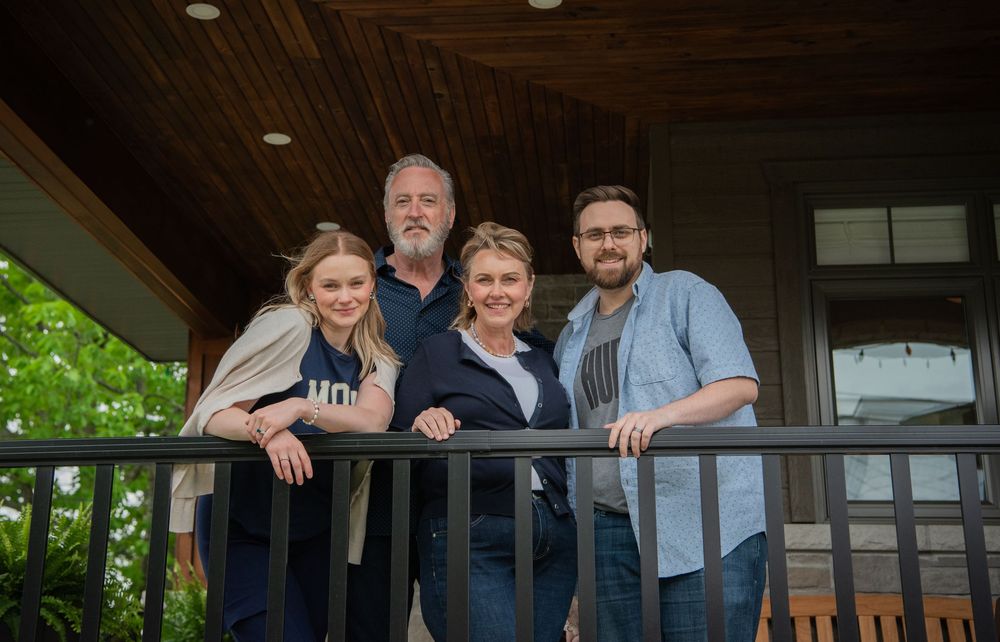 Group photo of people posing together on a covered outdoor porch.