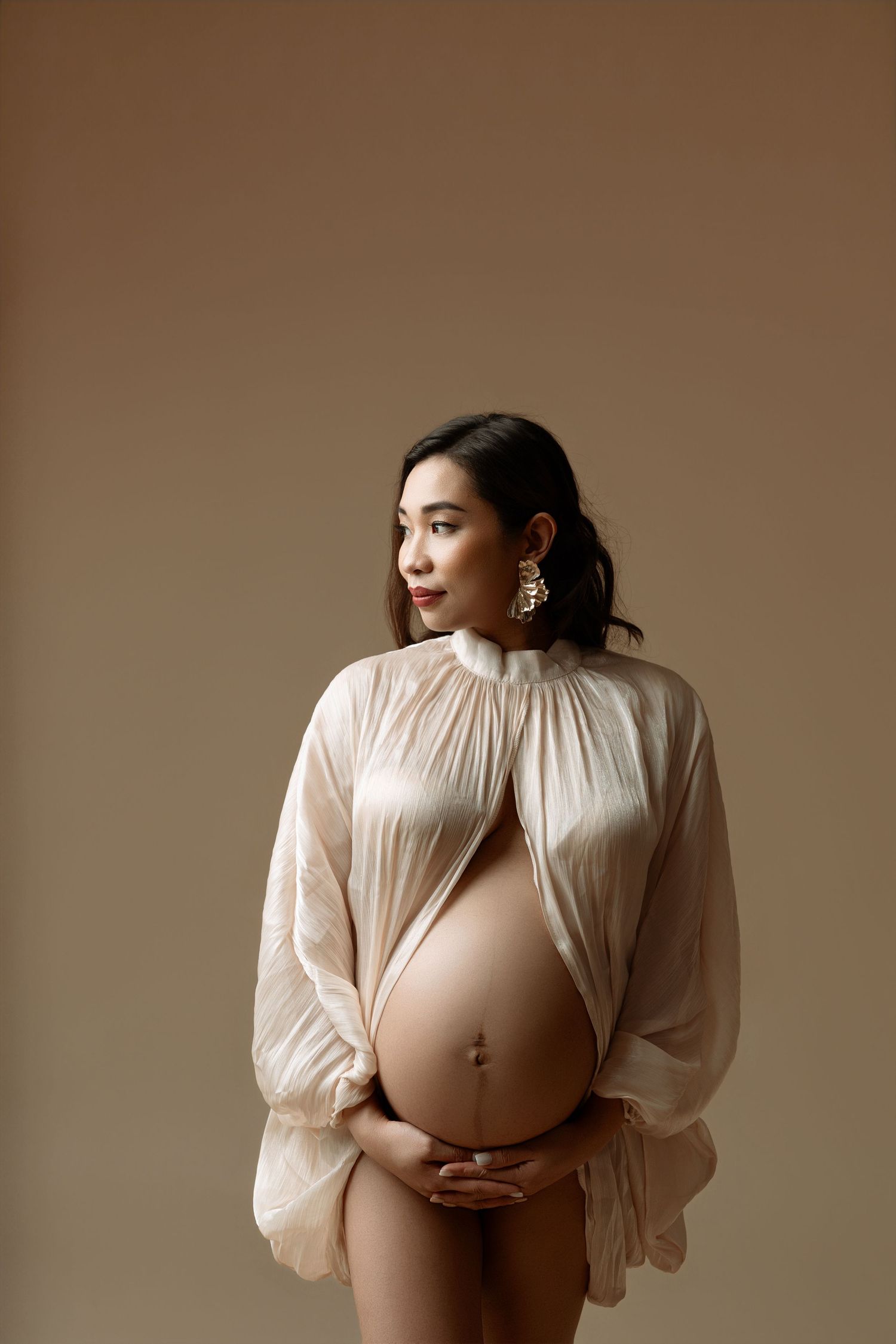 Intimate family maternity portrait in white and denim against brown backdrop.