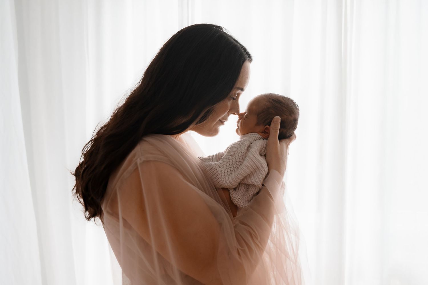 A silhouetted maternity photography sequence showing a woman in white by a bright window.