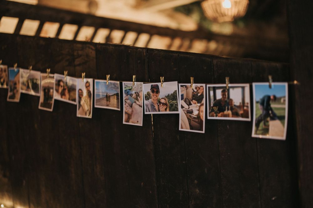 A string of vintage polaroid photographs hanging on a dark wall with clothespins against a moody background.