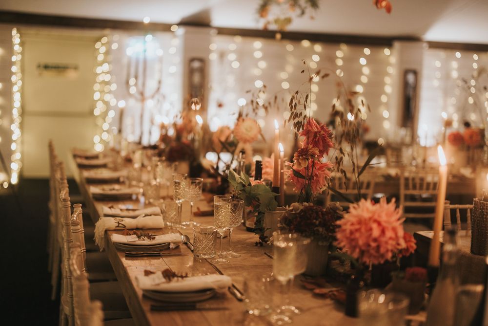 Elegant wedding reception venue with romantic candlelit tables and floral centerpieces in warm lighting atmosphere.