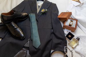 Formal men's suit with blue tie and accessories laid out on display.