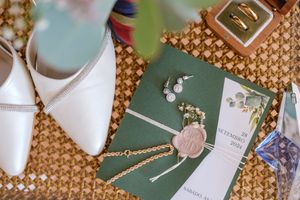 Wedding details and accessories arranged on woven textured surface with decorative elements.