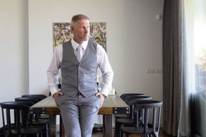 Interior photos of someone wearing a gray suit vest and white shirt in an elegant room.