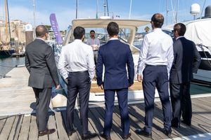 Group observing boats at a marina dock on a sunny day.