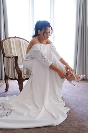 Elegant white wedding dress with embroidered details spread out on light carpeting.