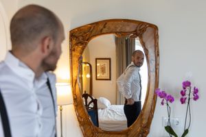 Wedding preparations in an elegant room with a gold-framed mirror and purple orchids.