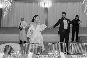 Black and white photo of wedding guests dancing and celebrating in an indoor venue.