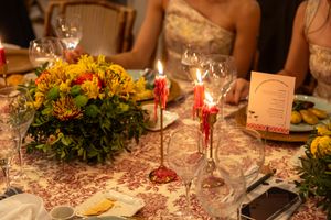 Wedding table setting with orange floral centerpiece and red candlesticks.