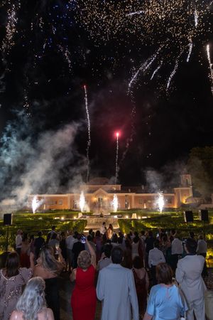 Spectacular fireworks and fountains illuminate grand building during nighttime celebration.