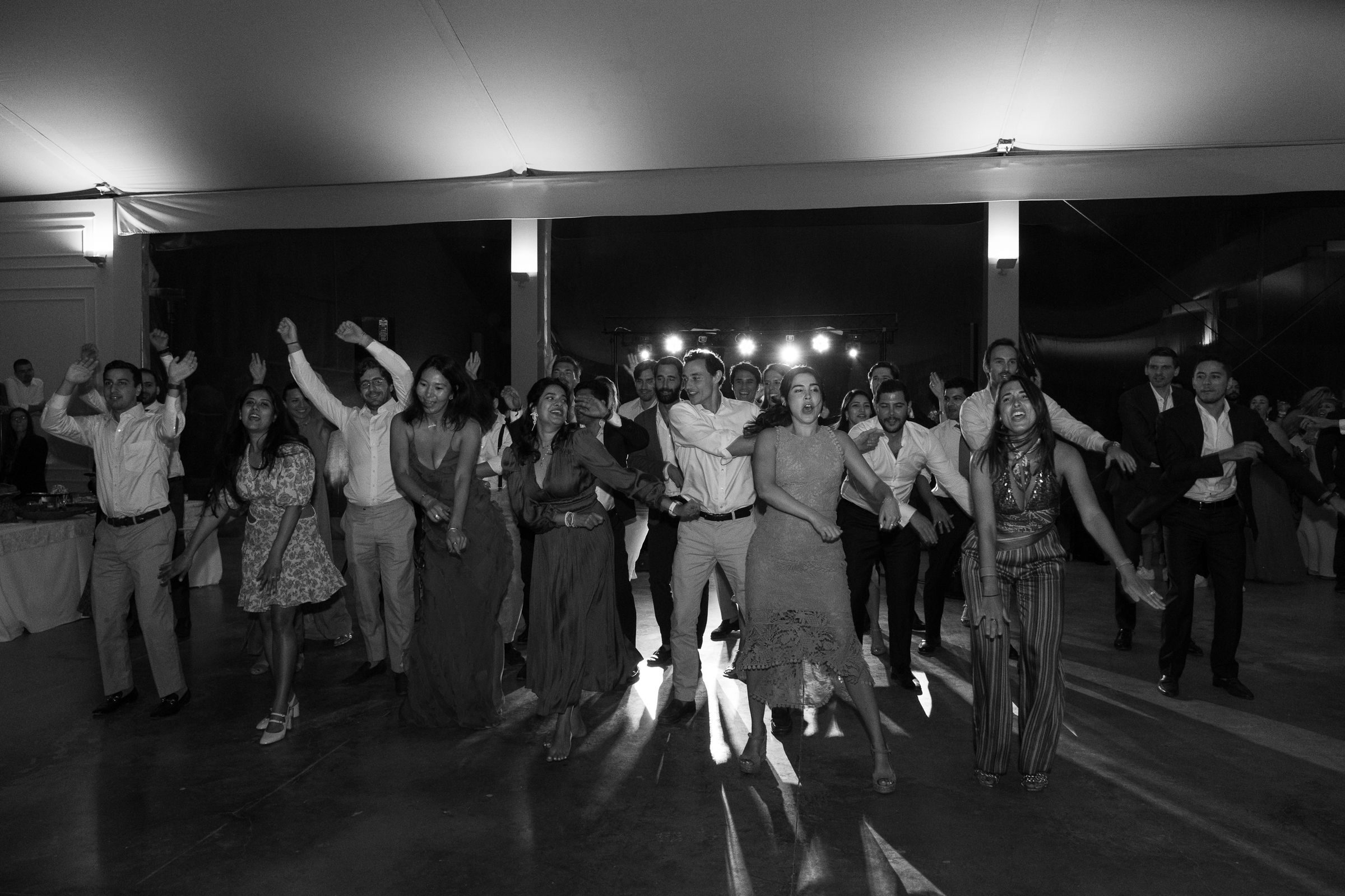 Black and white photo of wedding reception dance floor with guests celebrating.