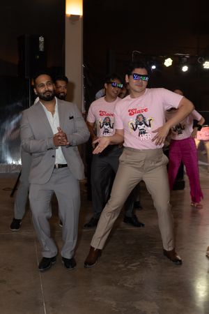 Wedding guests dancing and celebrating at indoor reception venue.
