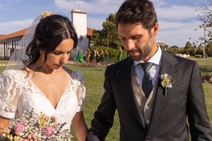 Newlyweds share intimate moment with bouquet in garden setting.
