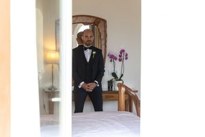 Classic formal attire being adjusted in bedroom mirror before special event.