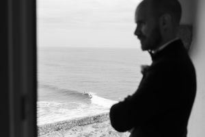 Silhouette by window overlooking coastal waves in dramatic black and white.