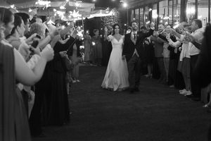 Black and white photo of a newlywed couple's first dance surrounded by guests at their reception.