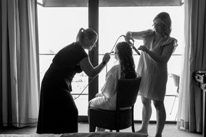 Silhouetted figures standing by large windows in an elegant interior space.