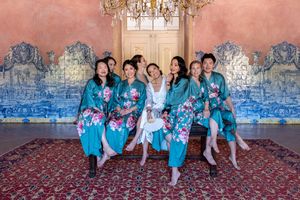 A group wearing matching turquoise floral robes posing in front of ornate blue and white tiles.