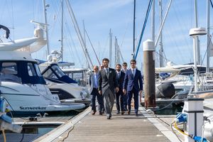 A group walking along a marina dock surrounded by luxury boats and yachts.