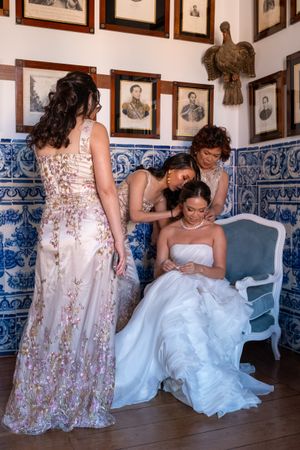 Wedding party in floral dresses and white gown sitting in a room with traditional Portuguese tiles.