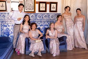 Wedding party in champagne colored dresses posing in an elegant room with blue tile walls.