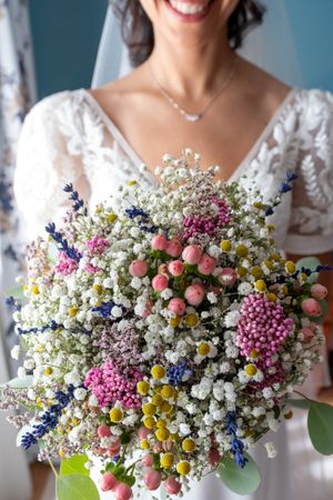 Colorful wildflower wedding bouquet with baby's breath, pink blooms and yellow daisies.