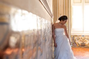 A wedding dress flows elegantly across an ornate room with gilded mirrors and antique furniture.