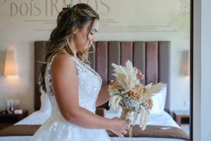 A bride in a lace wedding dress stands near an elegant decorative wall.