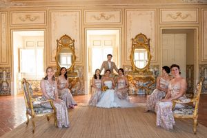 Wedding party poses in an elegant baroque room with ornate gold mirrors and decor.