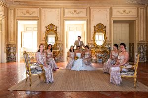 Panoramic shot of wedding party gathered in a luxurious baroque-style room.