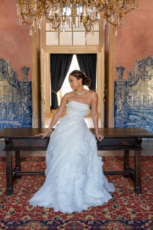 Wedding dress spreads across antique furniture in room with blue Portuguese azulejo tiles.