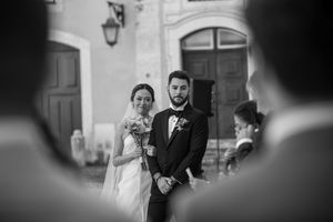 Wedding ceremony with bride and groom at altar captured through guests in black and white.