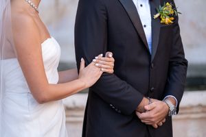 Close-up of bride and groom's formal attire showing wedding dress detail and boutonniere.