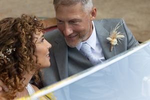 Intimate moment between wedding couple captured through reflective car surface.